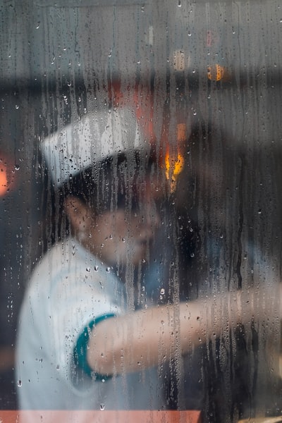 透过雨中的窗户看到正在工作的厨师